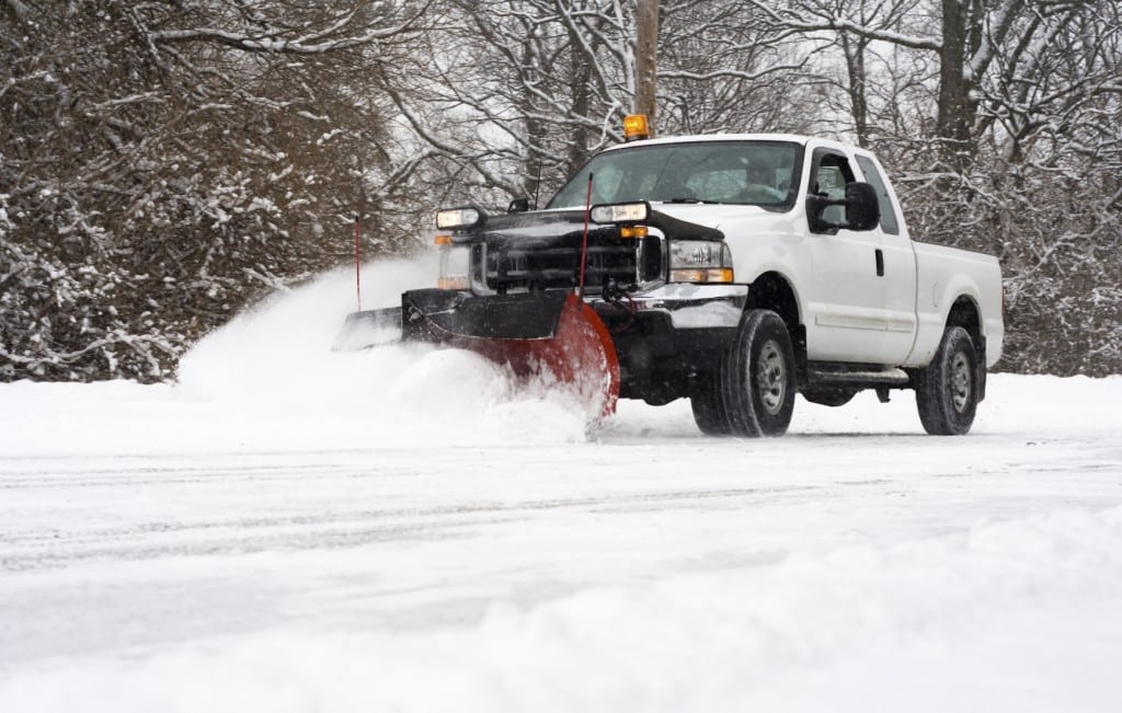 Man in pickup truck plowing road during snow storm Risingers Landscaping